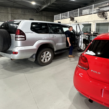 image of mechanic climbing out out toyota prada on AAEM workshop floor